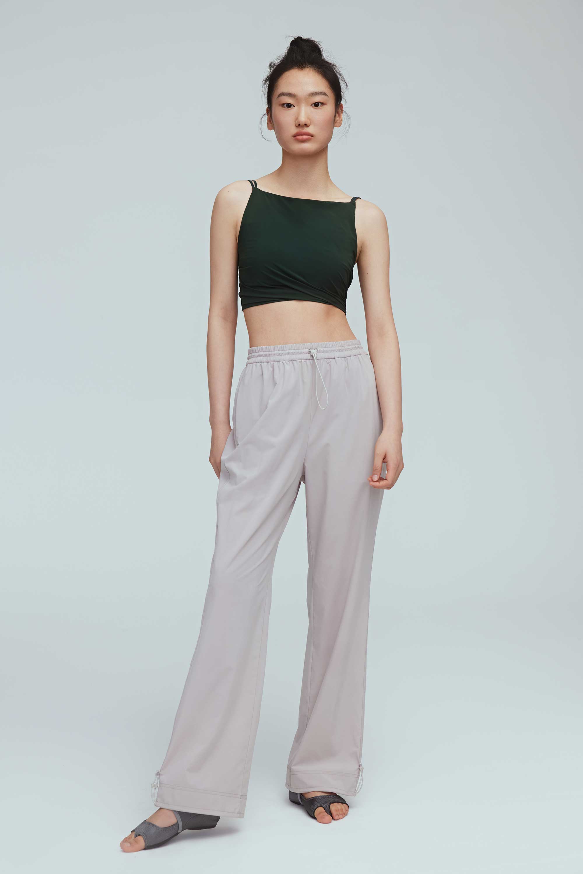 a woman wearing a grey joggers and green sports bra