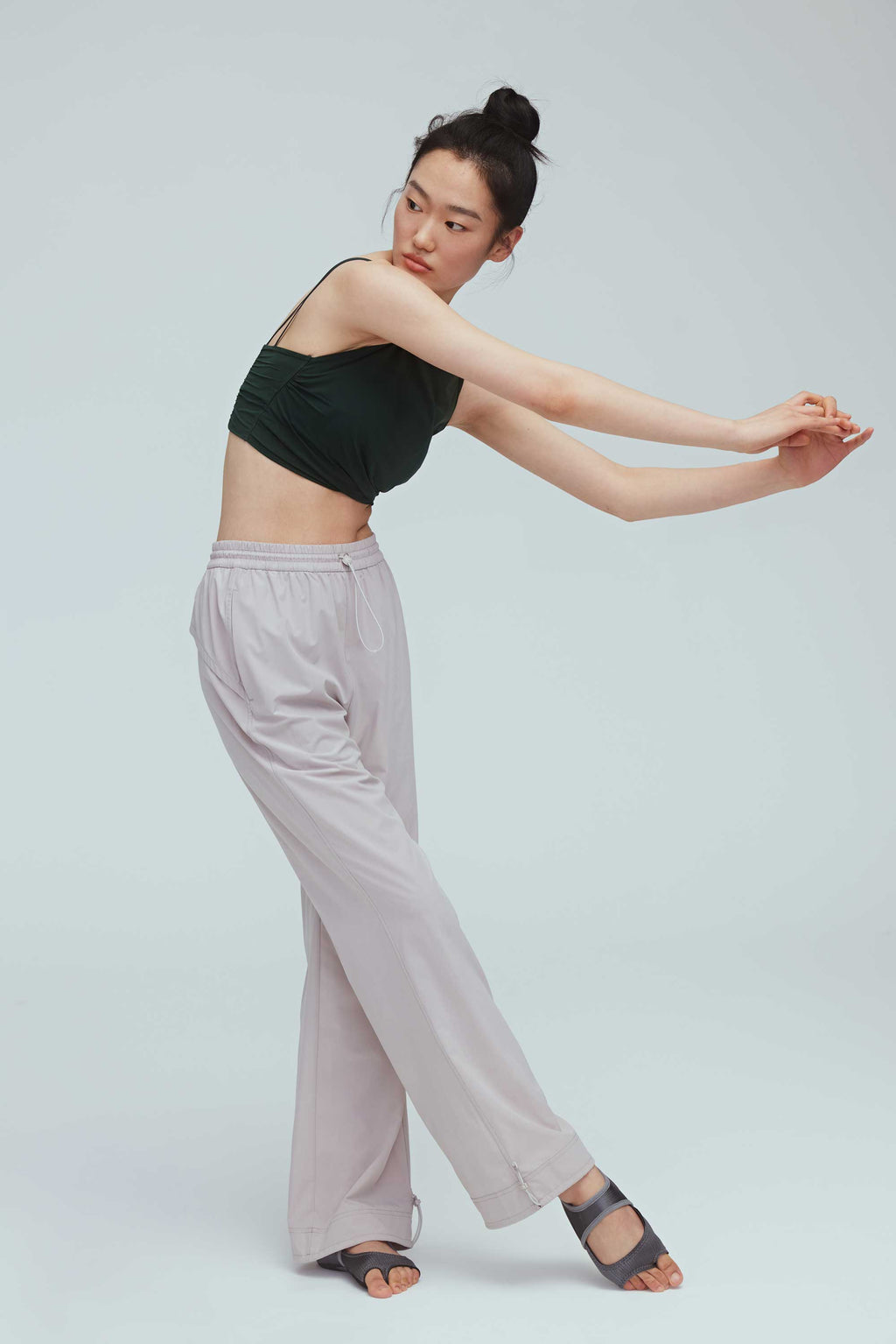 a woman wearing a grey joggers and green sports bra 