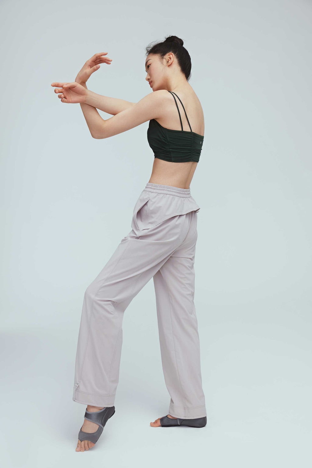 back of a woman wearing a grey joggers and green sports bra