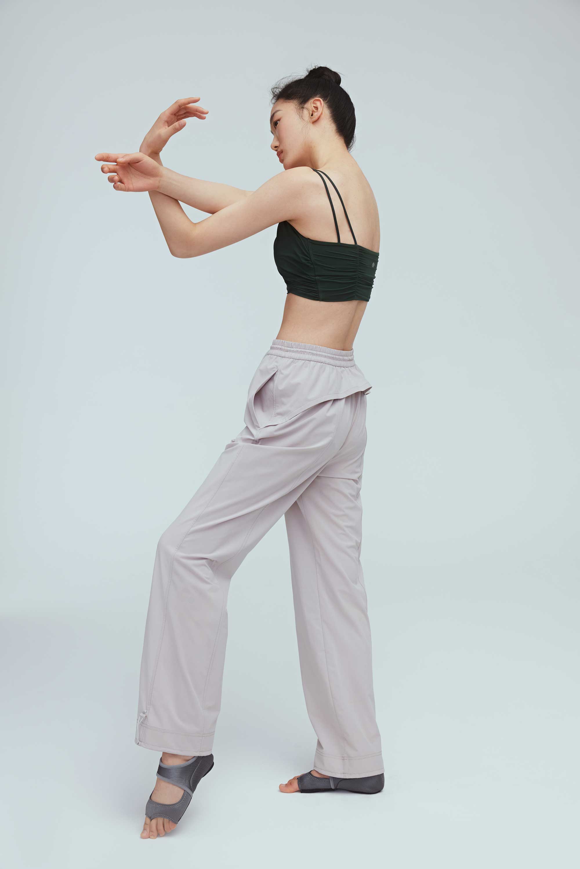 back of a woman wearing a grey joggers and green sports bra