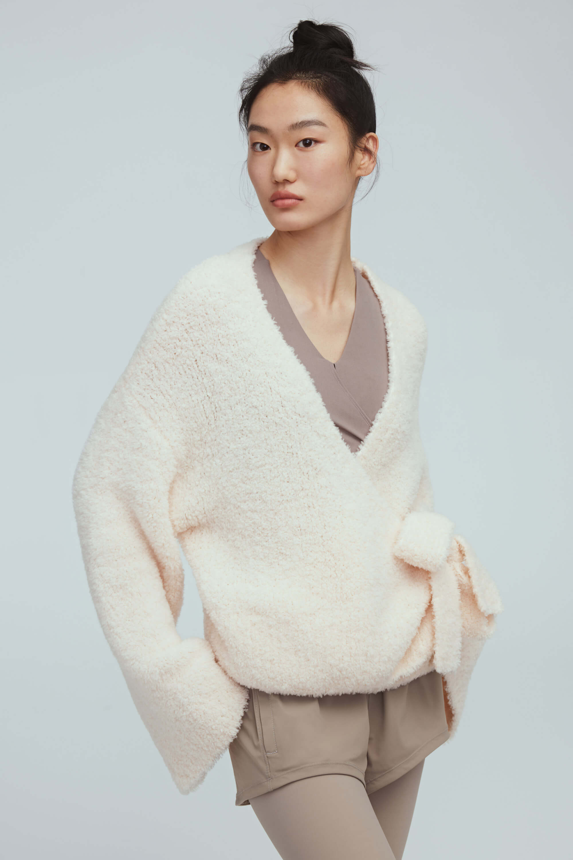 a woman wearing a white wool wrap cardigan and light grey leggings.