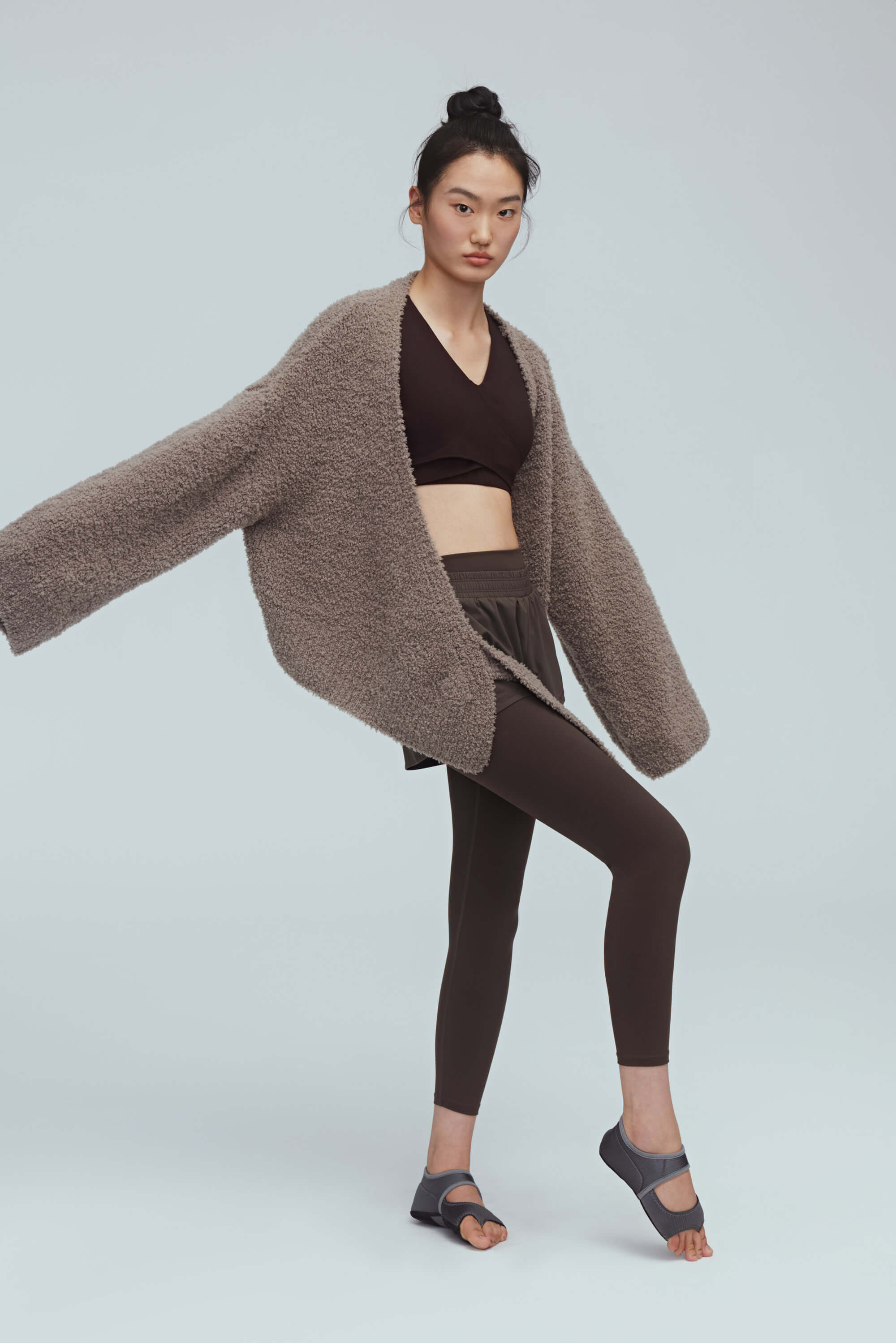  woman wearing taupe cardigan and brown sports bra and brown leggings