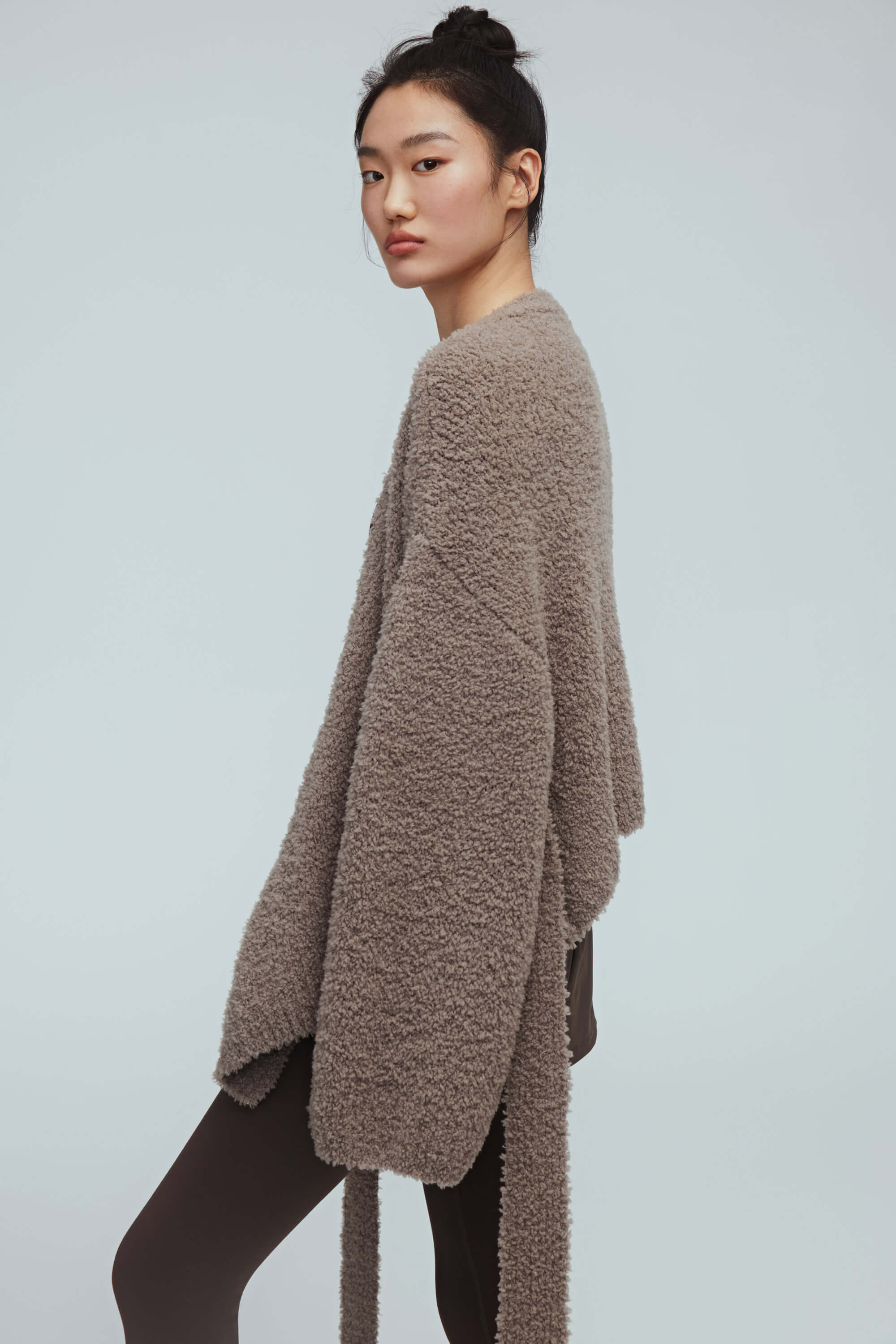 side of a woman wearing taupe cardigan and brown leggings 