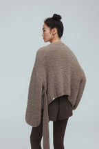 back of a woman wearing taupe cardigan and brown leggings