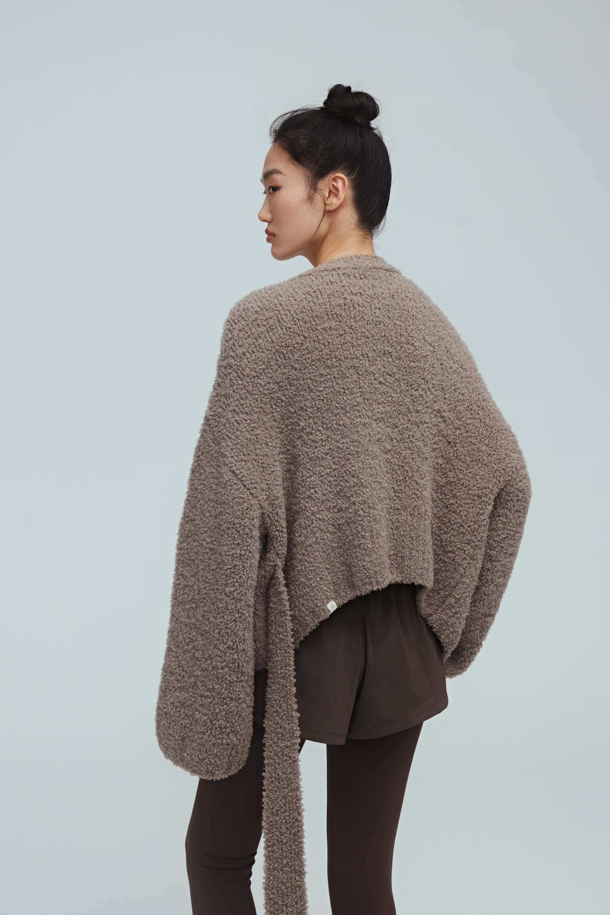 back of a woman wearing taupe cardigan and brown leggings