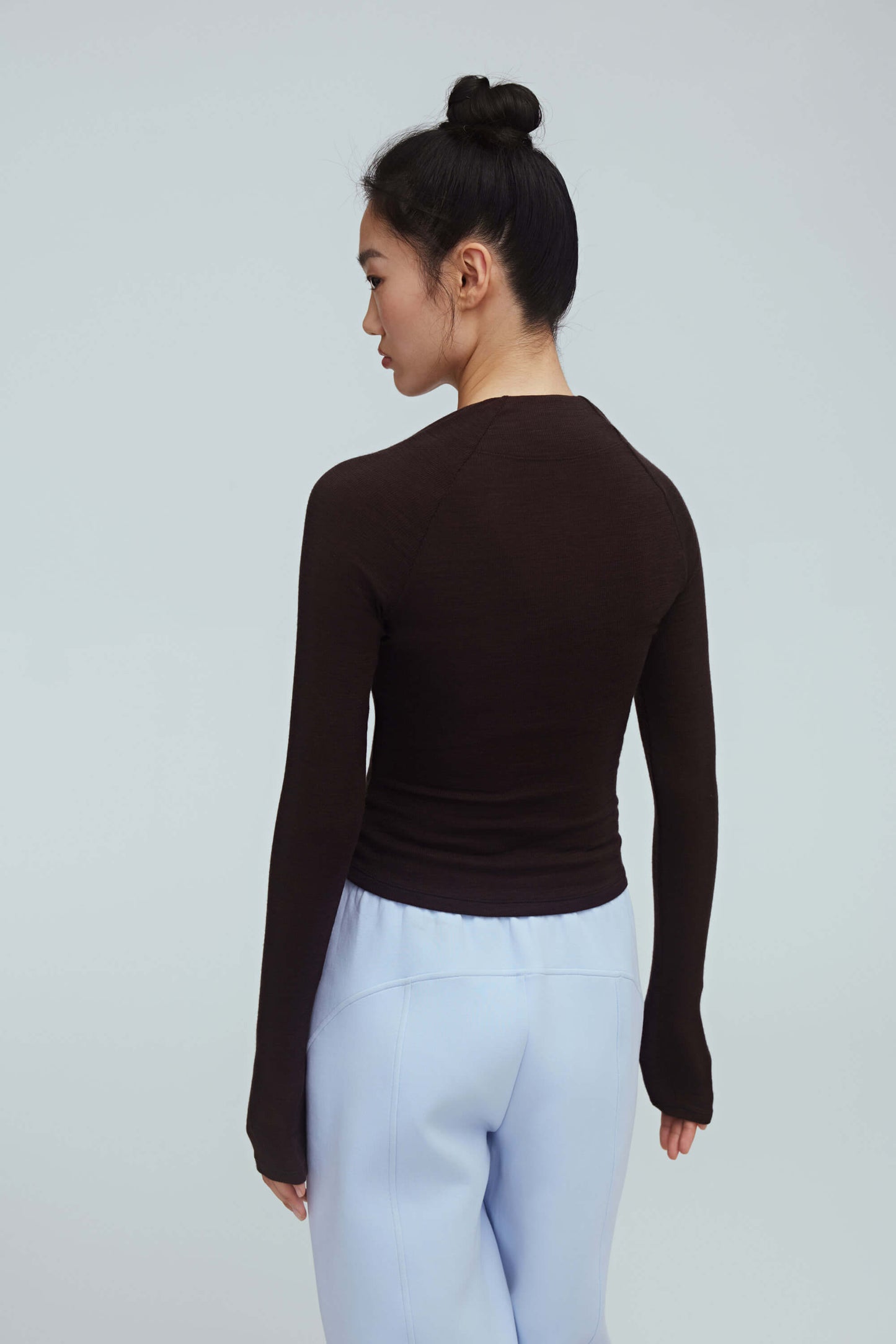 back of a woman wearing a brown ballet wool shirt and blue pants