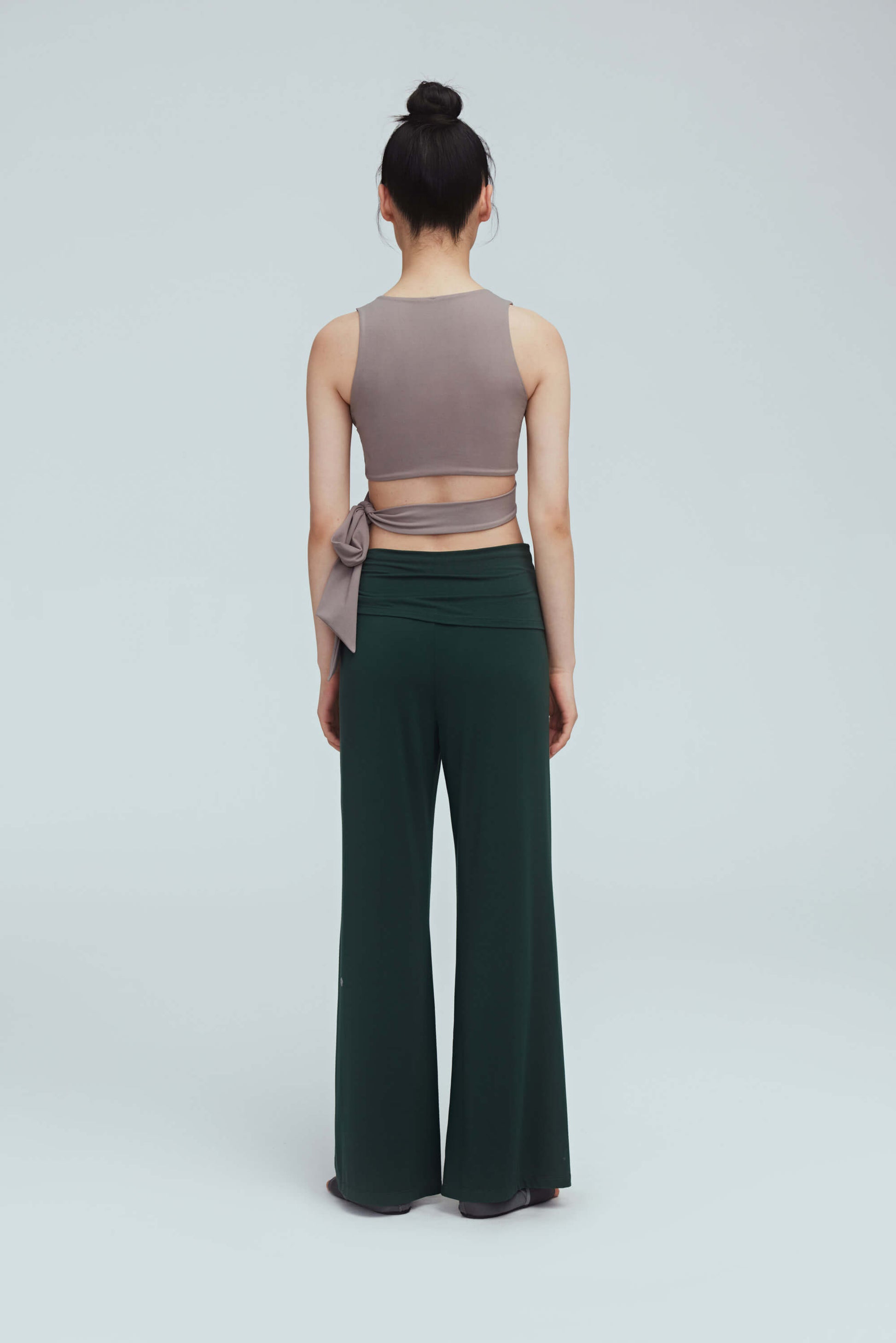 back of a woman wearing a light brown wrap bra top and green leggings