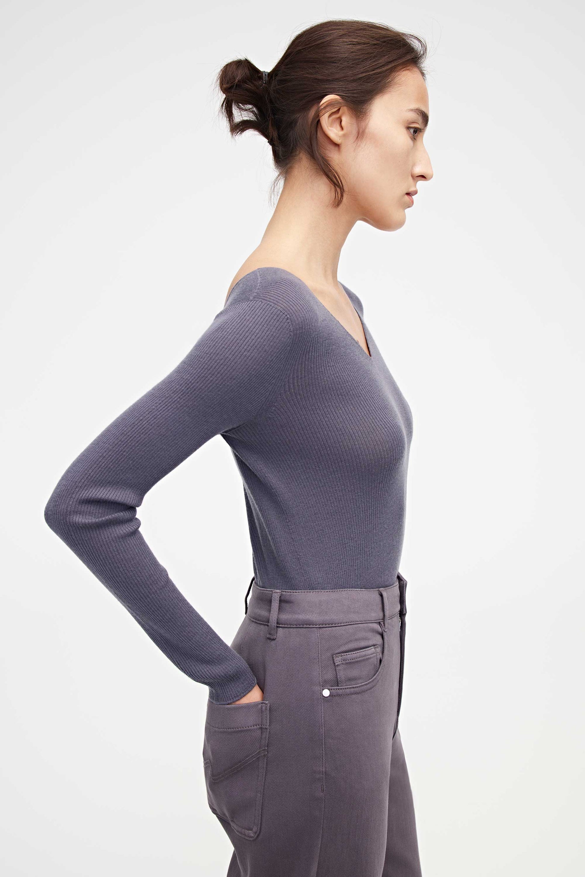 side look of woman in purple v neck sweater