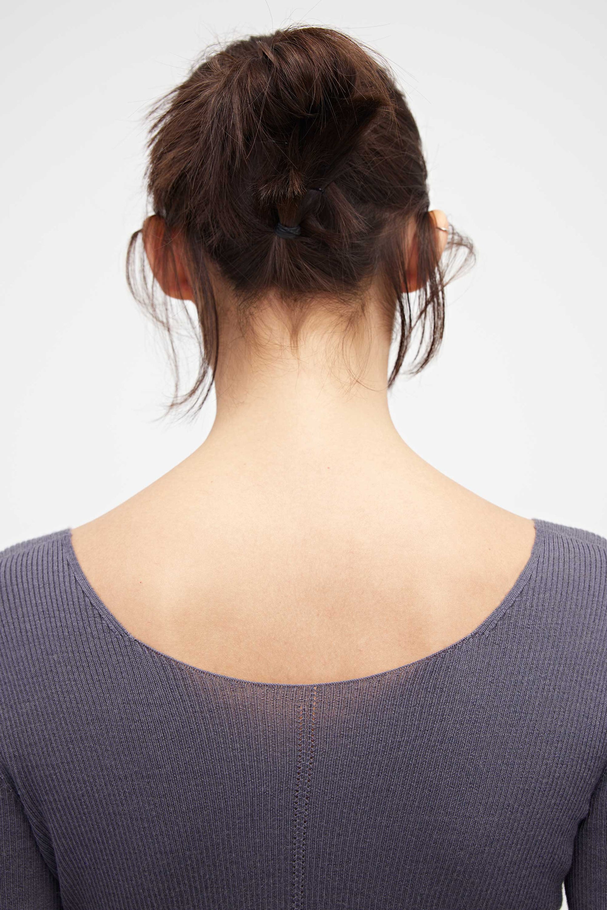 close up of woman in purple v neck sweater from back