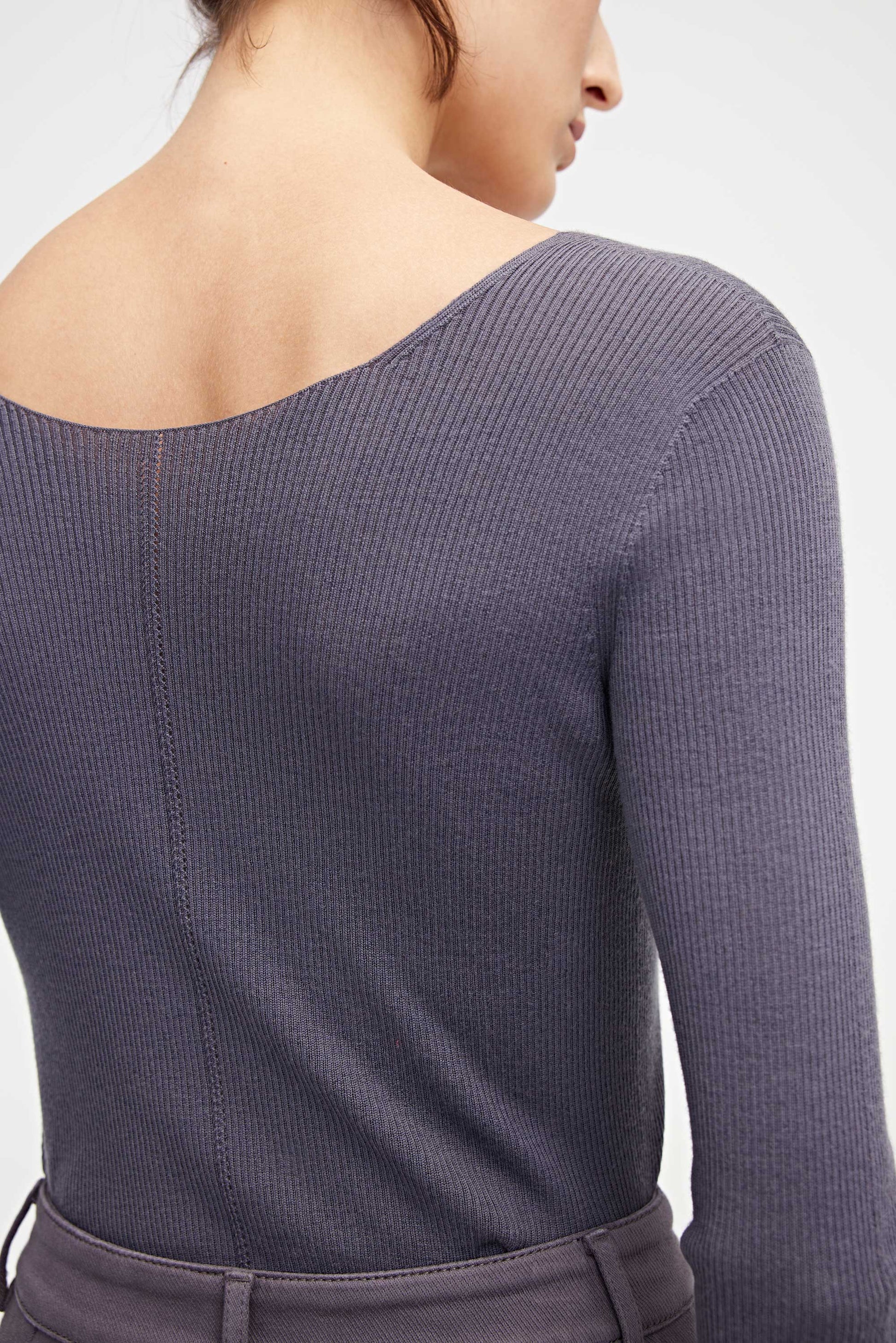 back of woman in purple v neck sweater