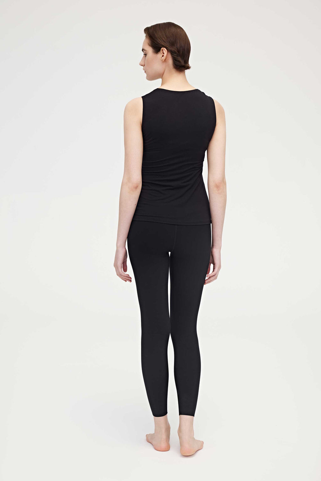 Back side of woman wearing black tank top and leggings