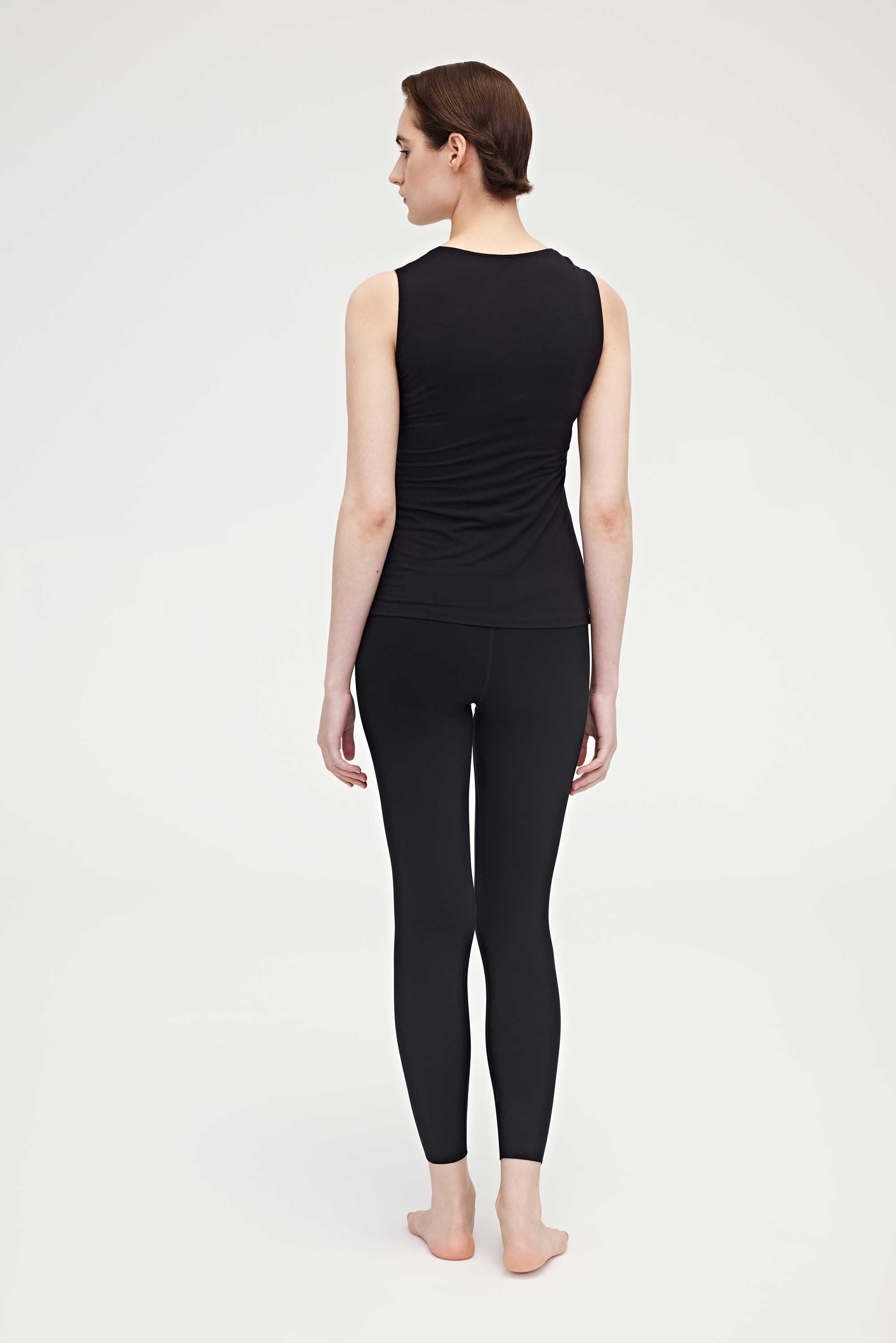 Back side of woman wearing black tank top and leggings