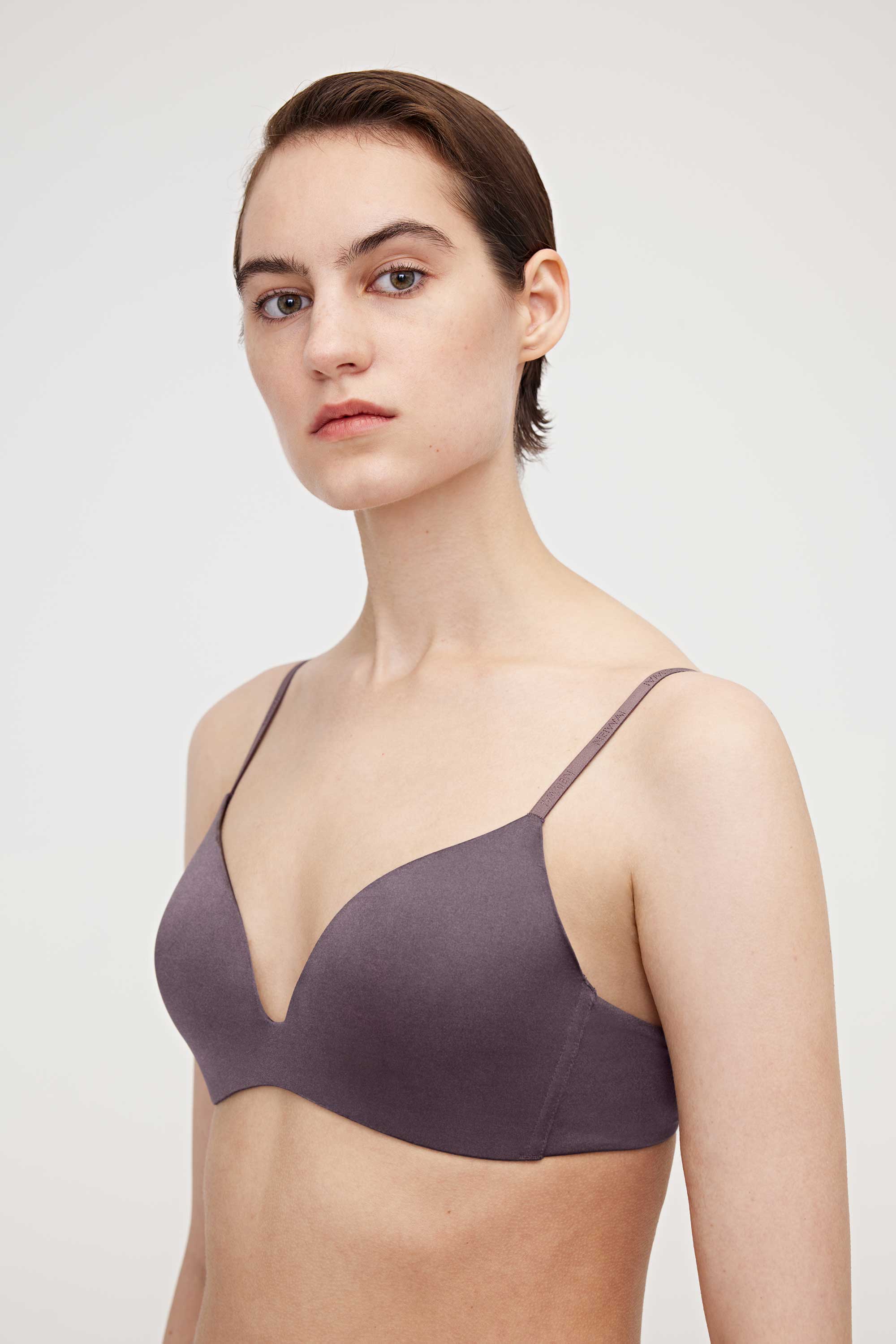 A woman wearing a purple bra and facing left