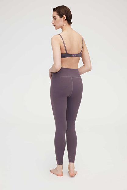 Back side of woman wearing purple bra and leggings