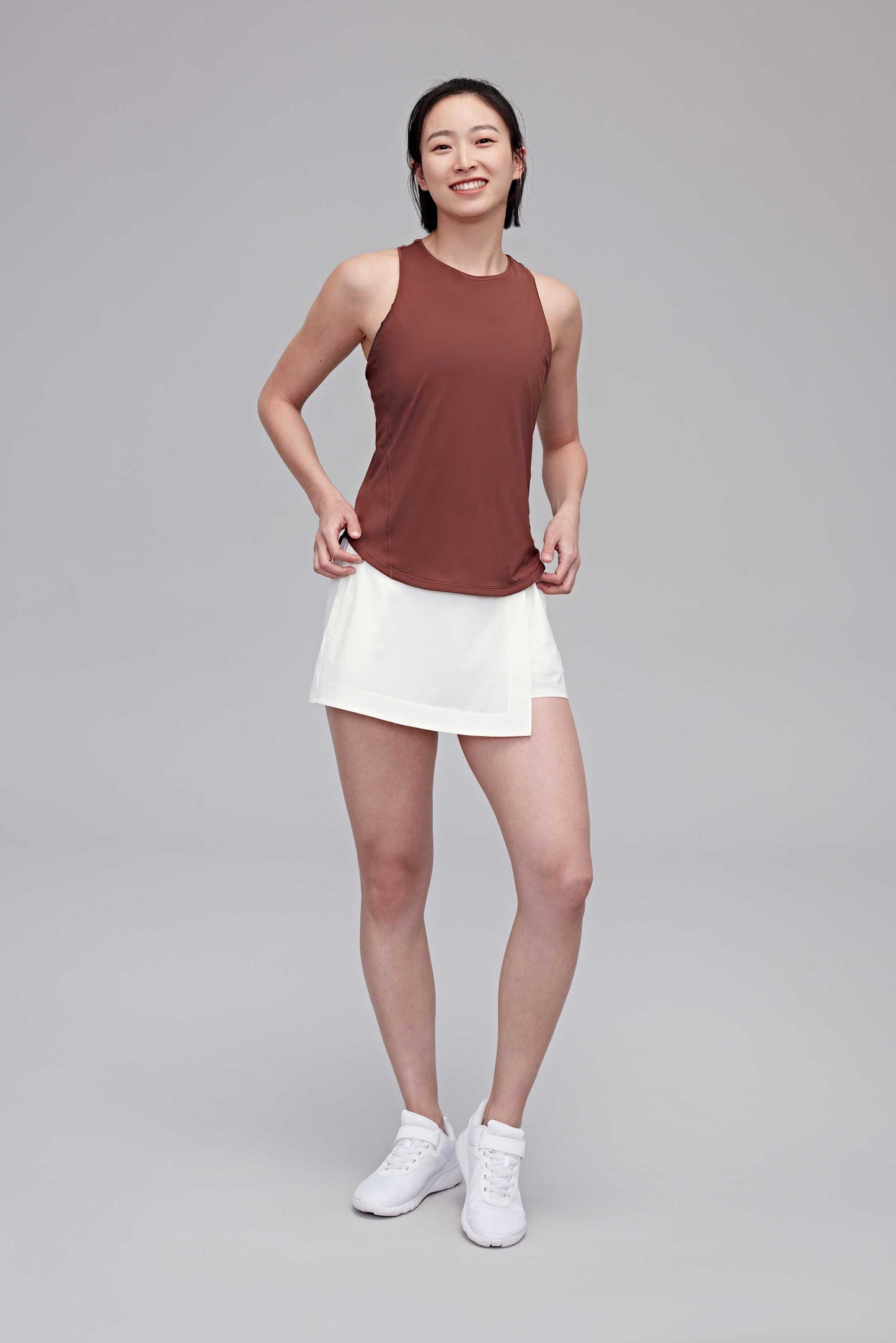 woman in reddish brown tank and white shorts