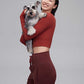 A woman wearing a red top and holding a dog