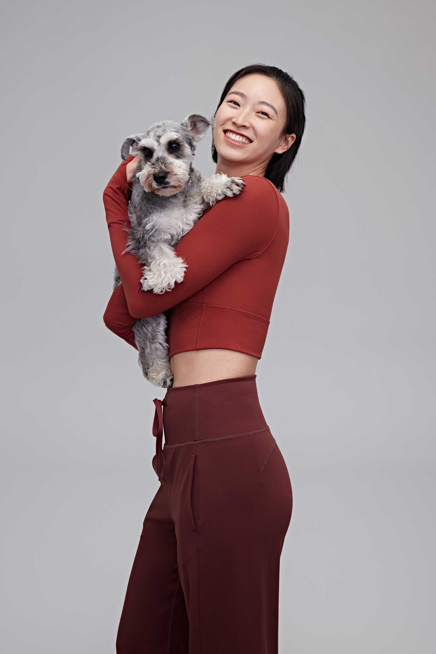 A woman wearing a red top and holding a dog