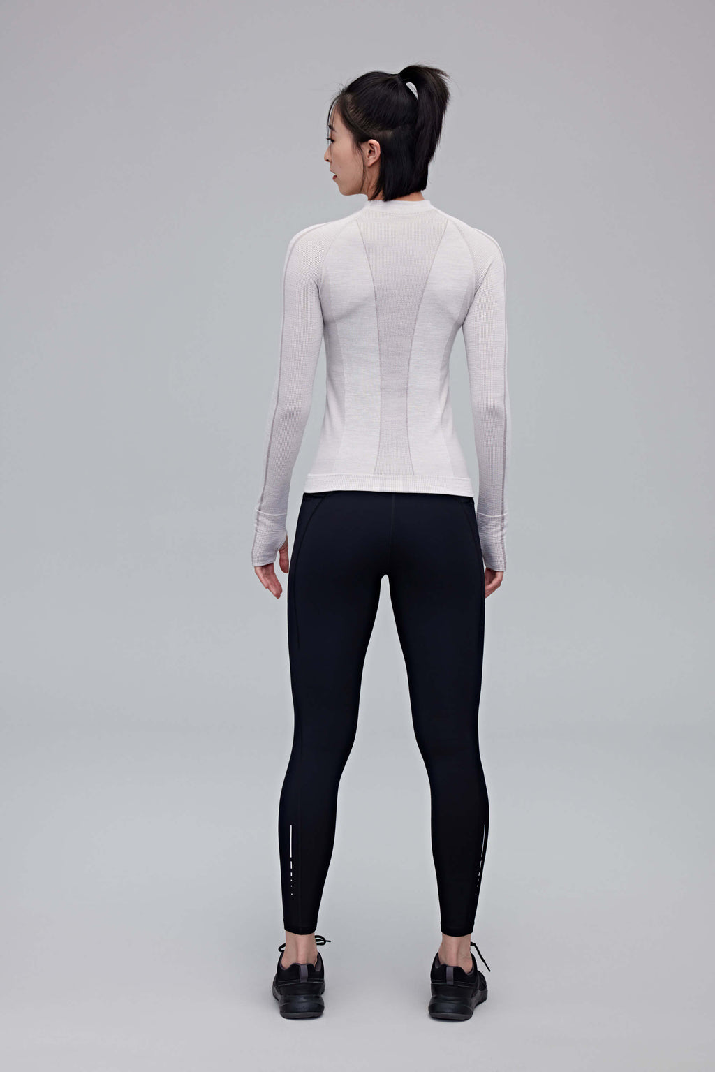 back of woman in black leggings and grey top