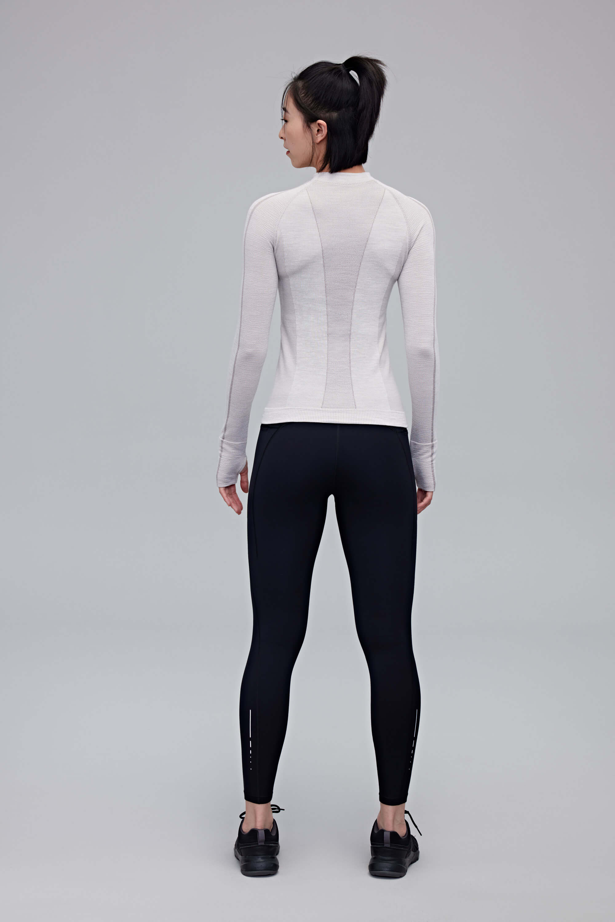 back of woman in black leggings and grey top