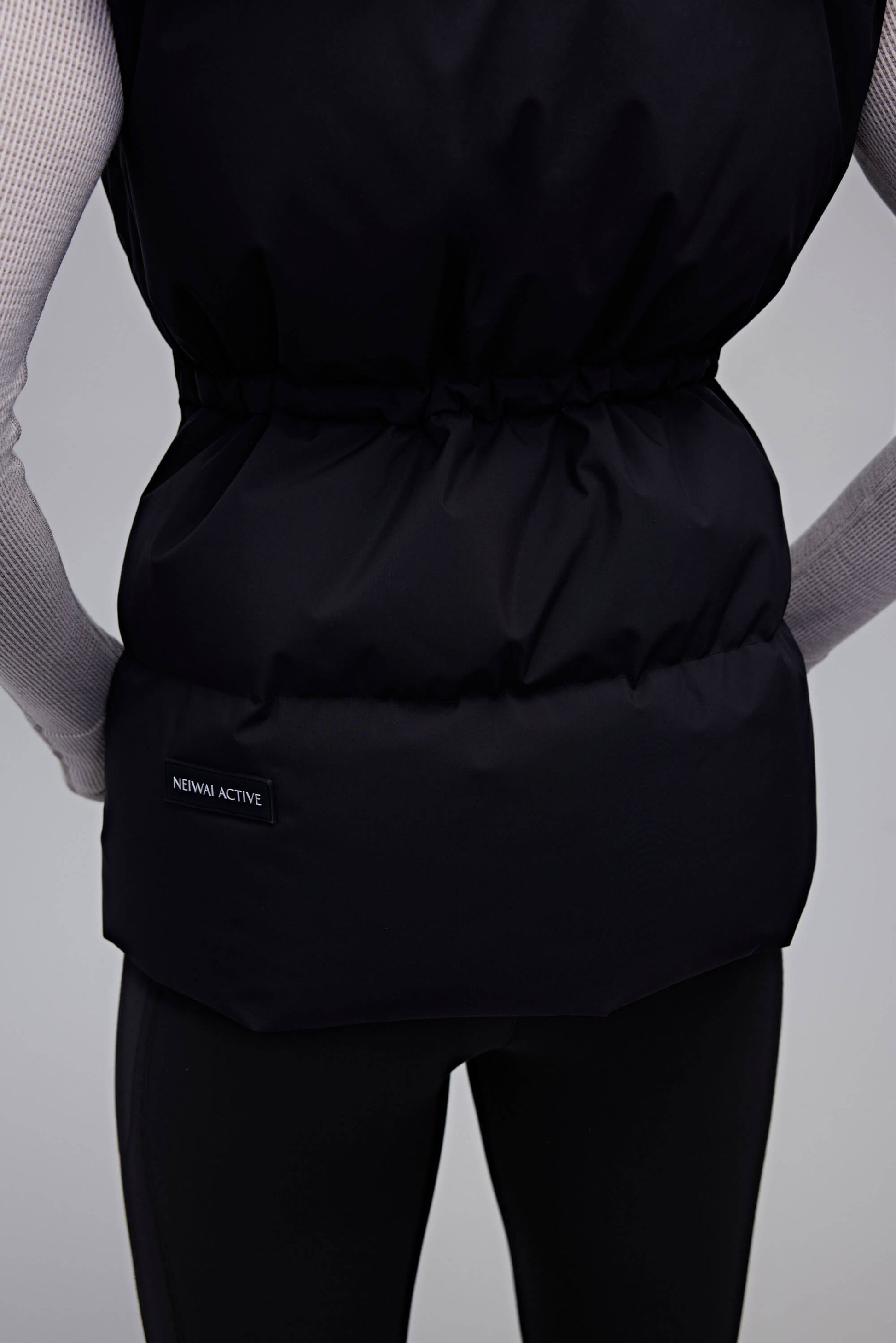 back of woman in black down vest