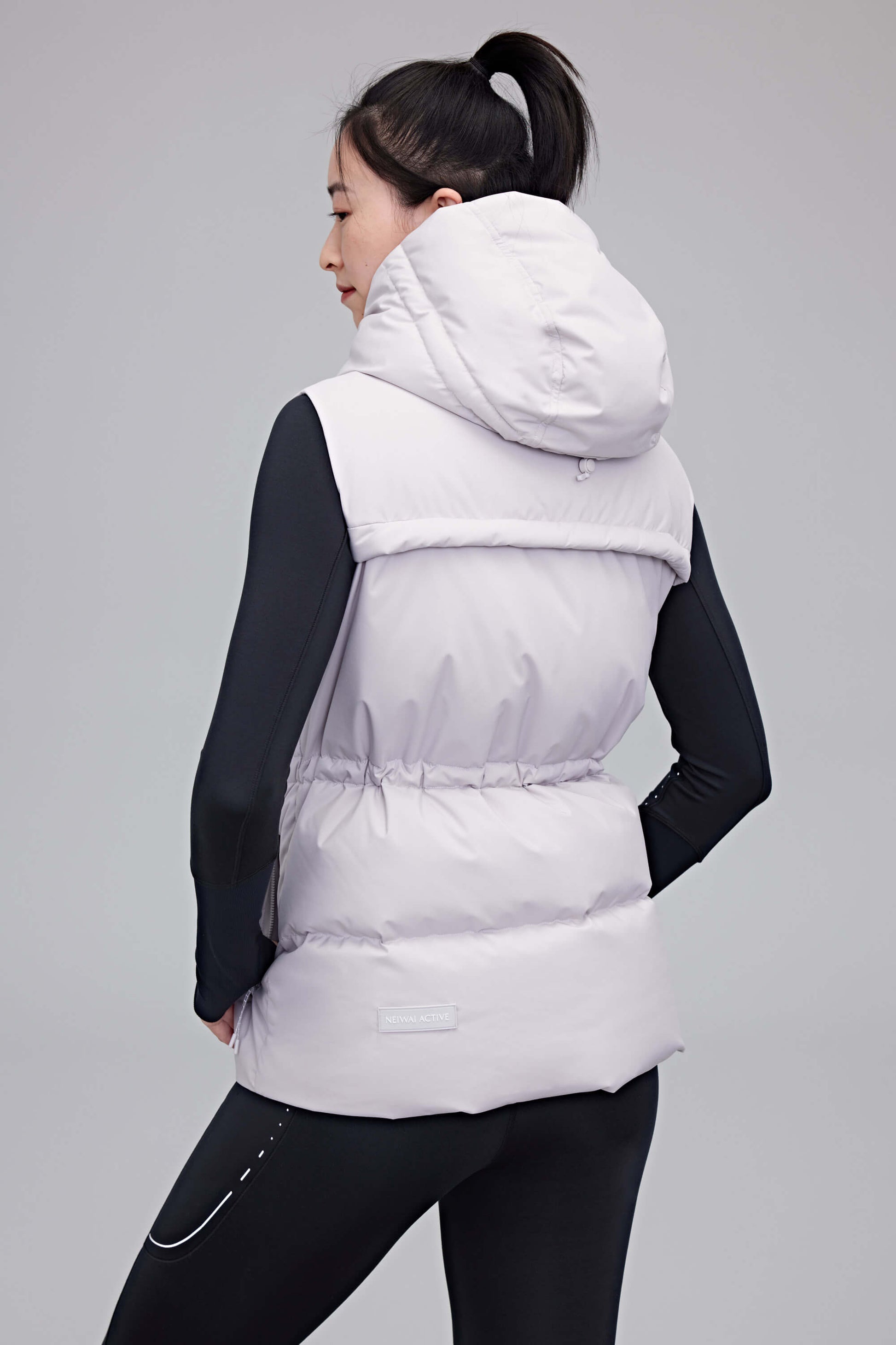 back of woman in grey hooded down vest