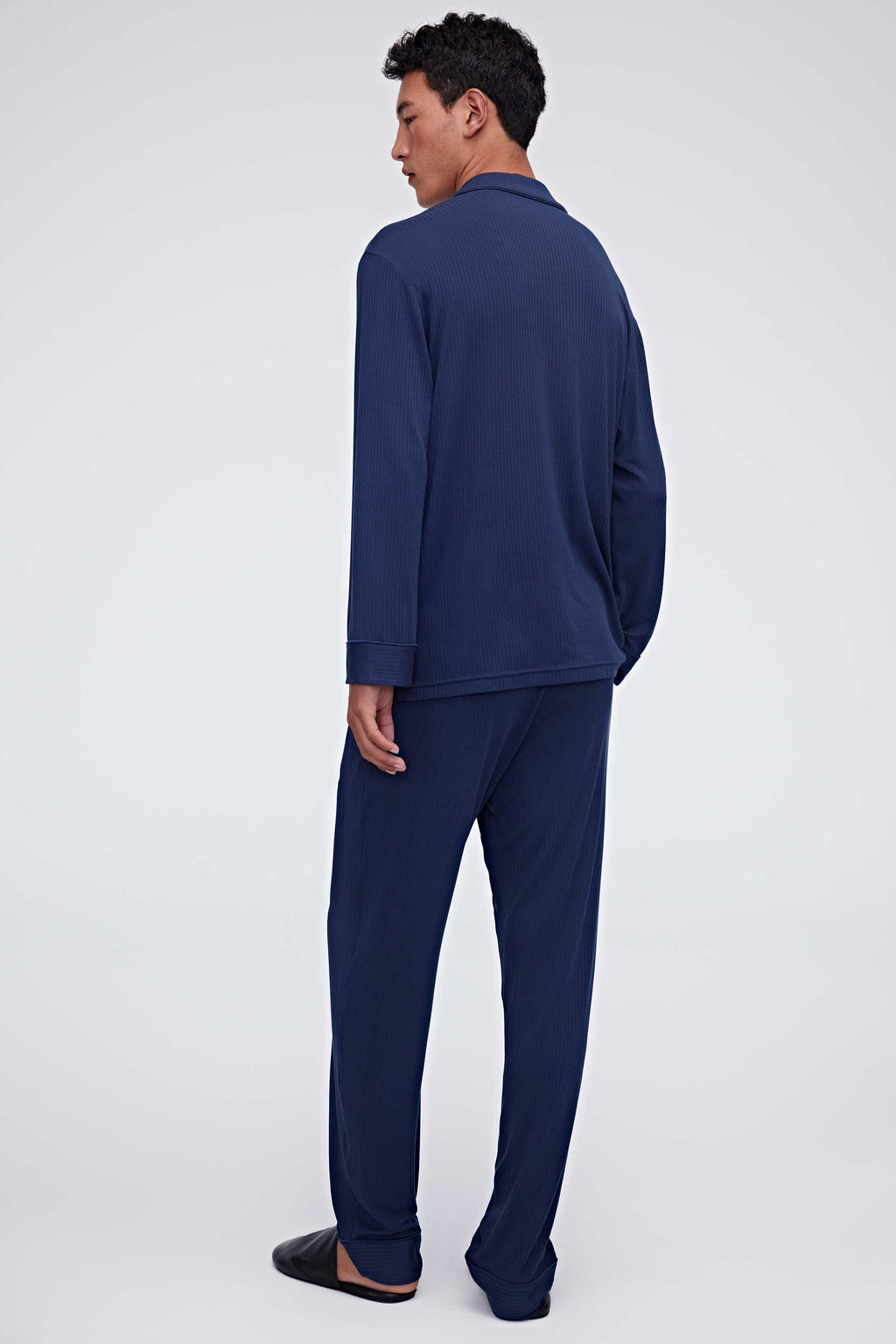 back of man in navy pajama button up shirt and pants