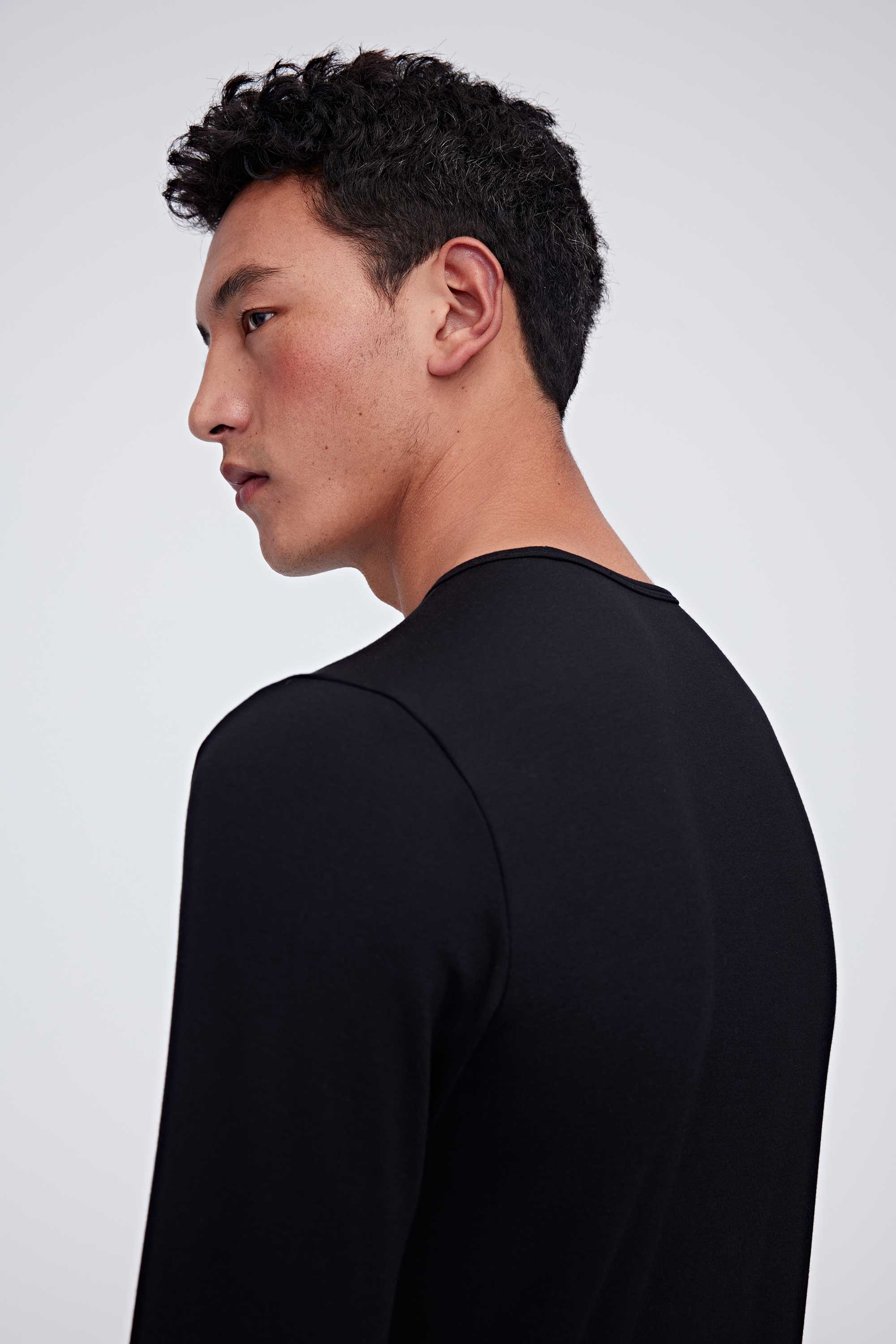 A man wearing a black thermal top and facing left