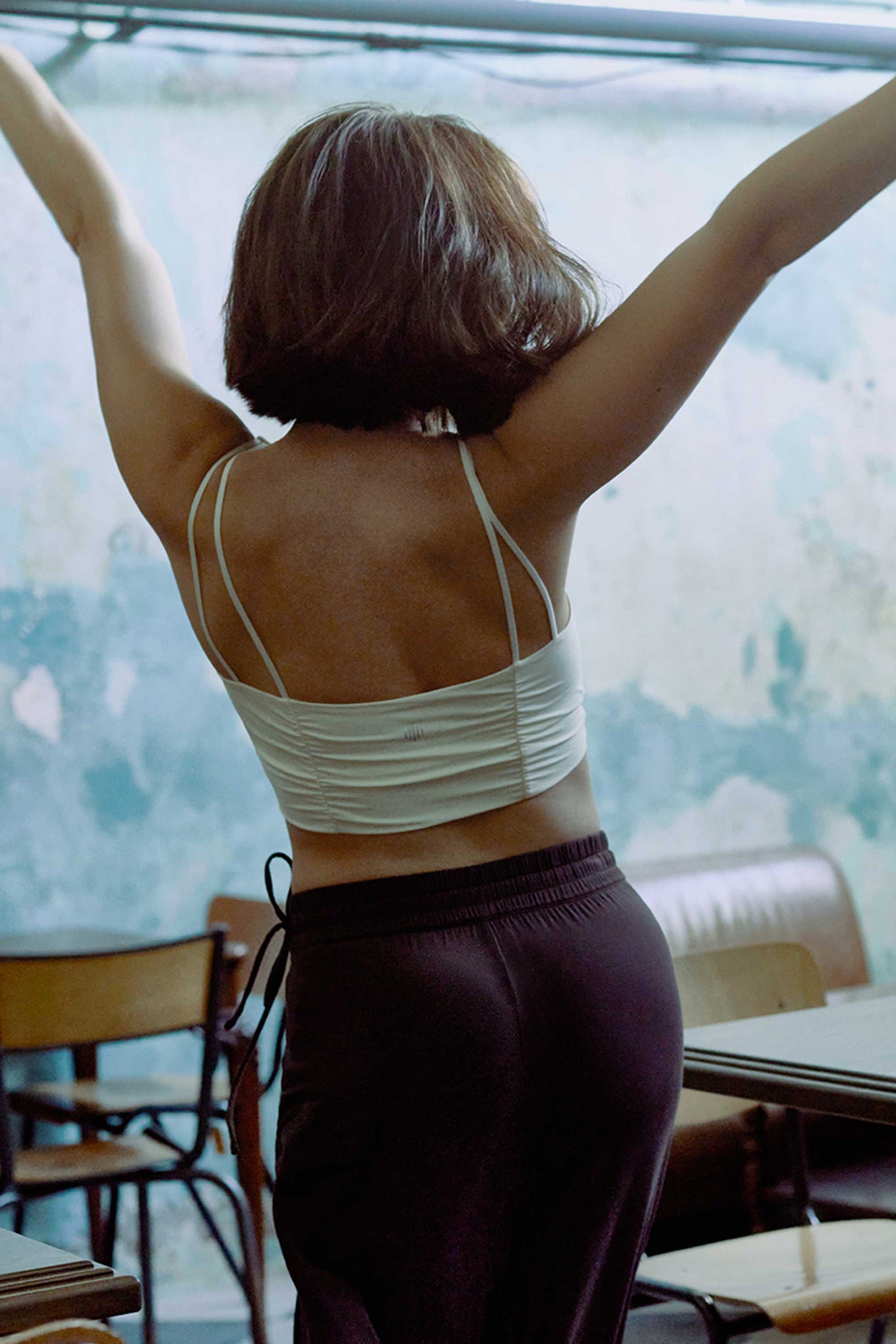 A back view of a woman wearing a white sports bra with pleats details.