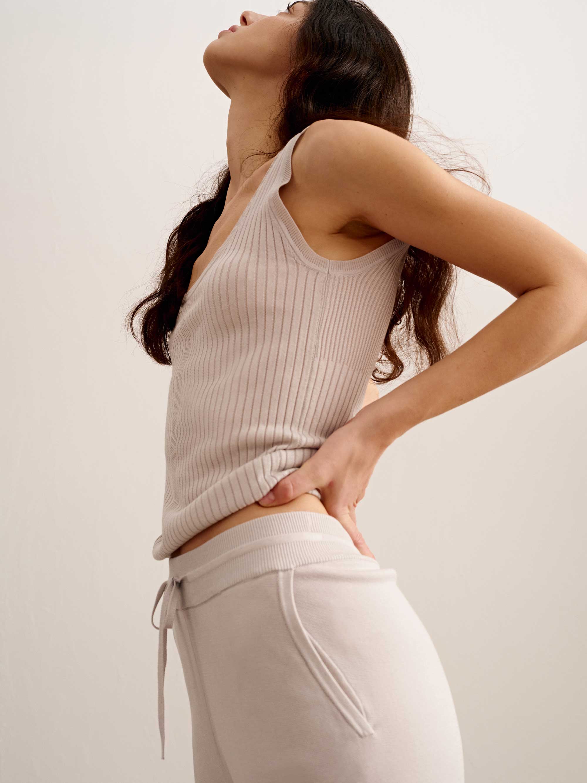 side of woman in light pink tank top and joggers