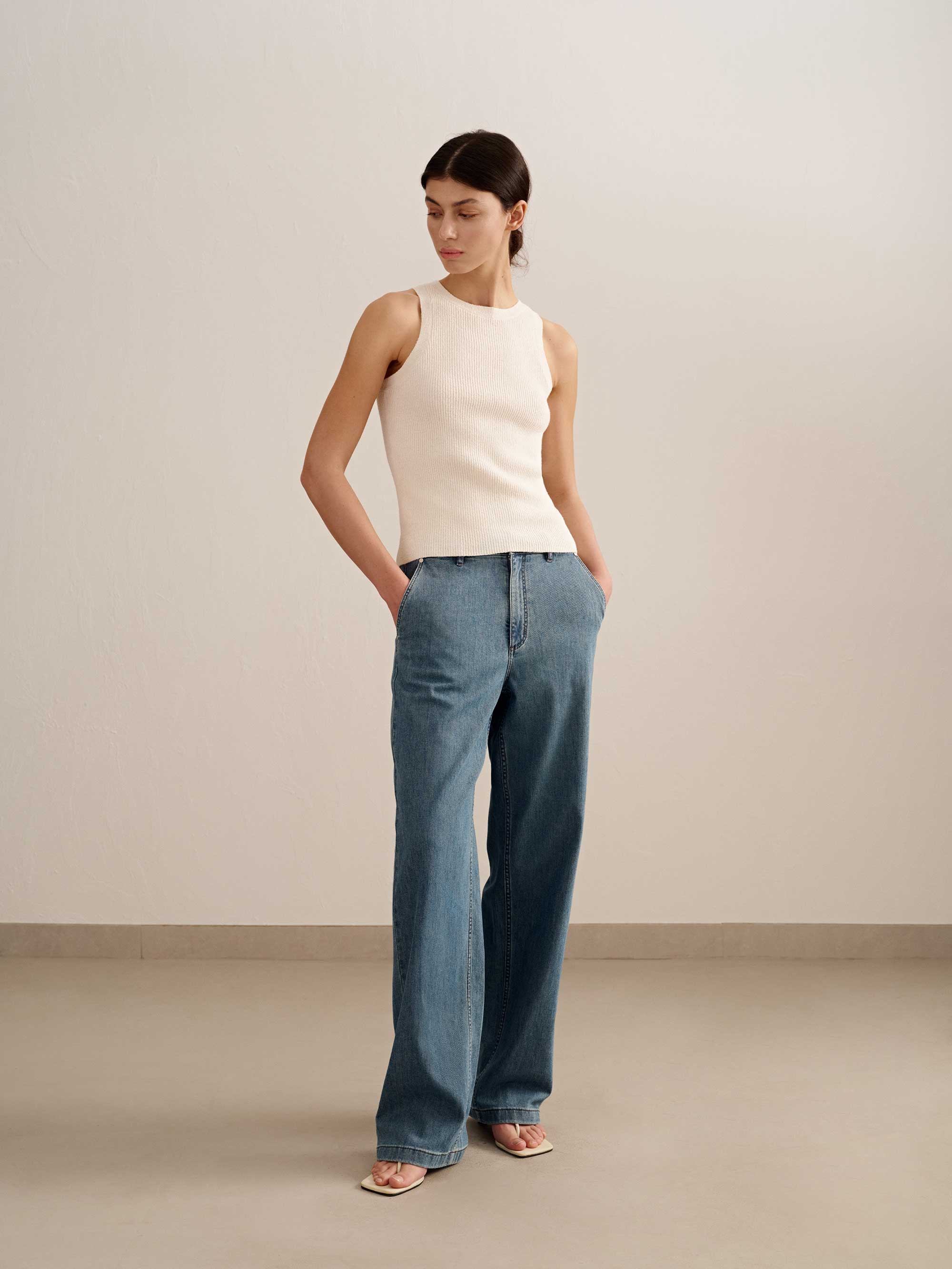 woman wearing a white tank and blue jeans