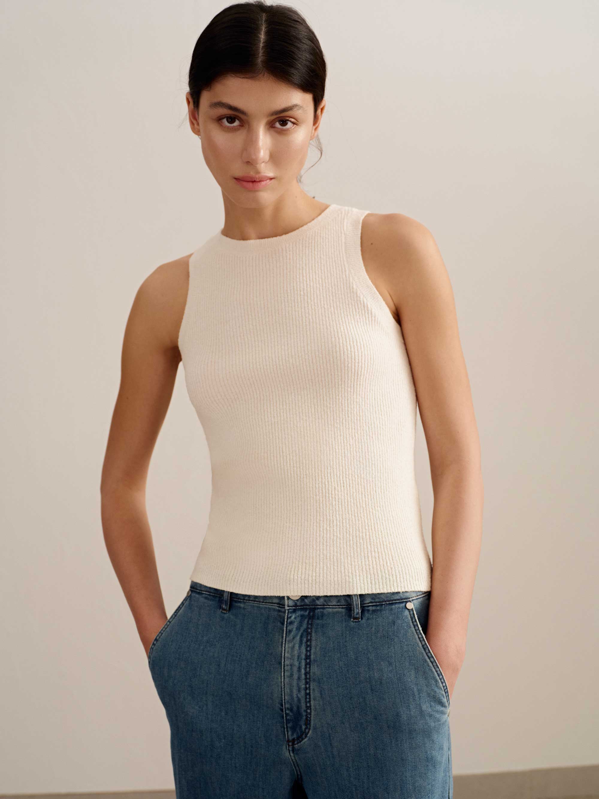 woman wearing a white tank and blue jeans