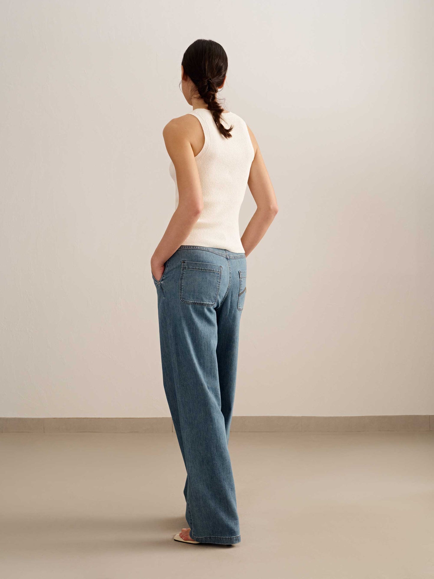 back of a woman wearing a blue tank and blue jeans