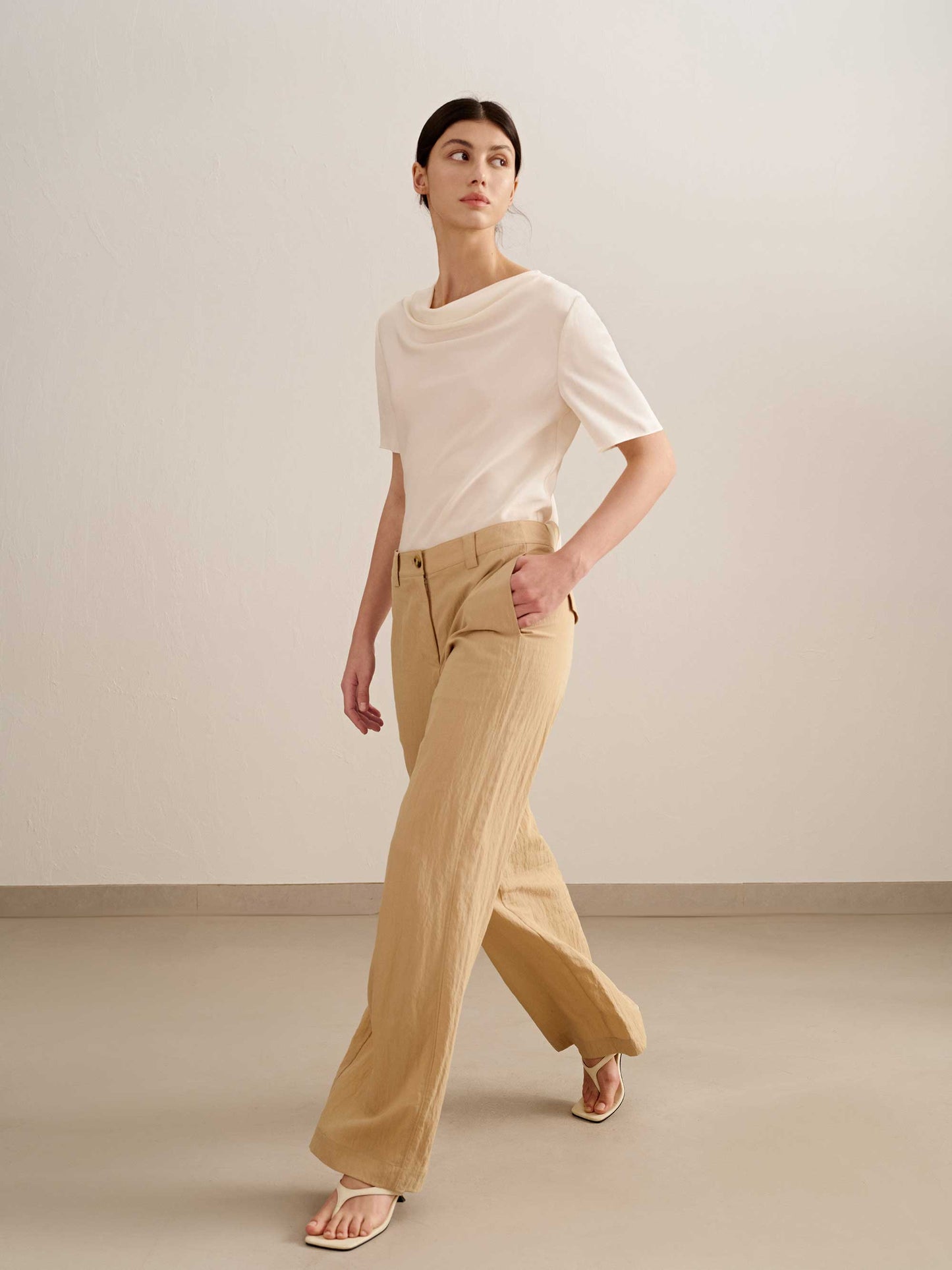a woman walking,  wearing a yellow wide leg trousers with white tee