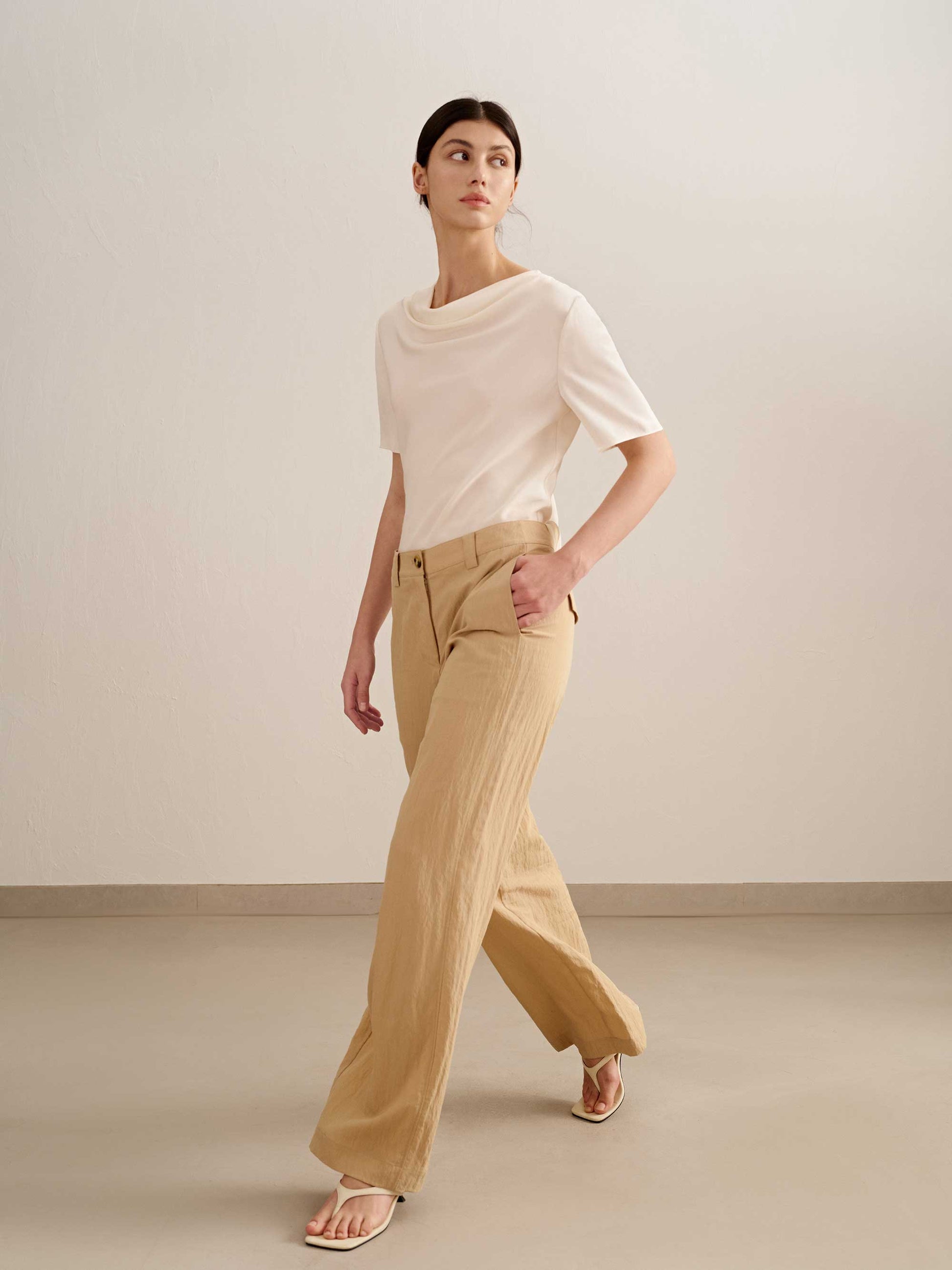 a woman walking,  wearing a yellow wide leg trousers with white tee