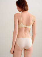 back of woman in cream bra and brief