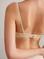 back of a woman wearing a light beige bra with clasp. 