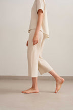 side of a woman wearing a light beige short sleeve tee with light beige cropped pants.