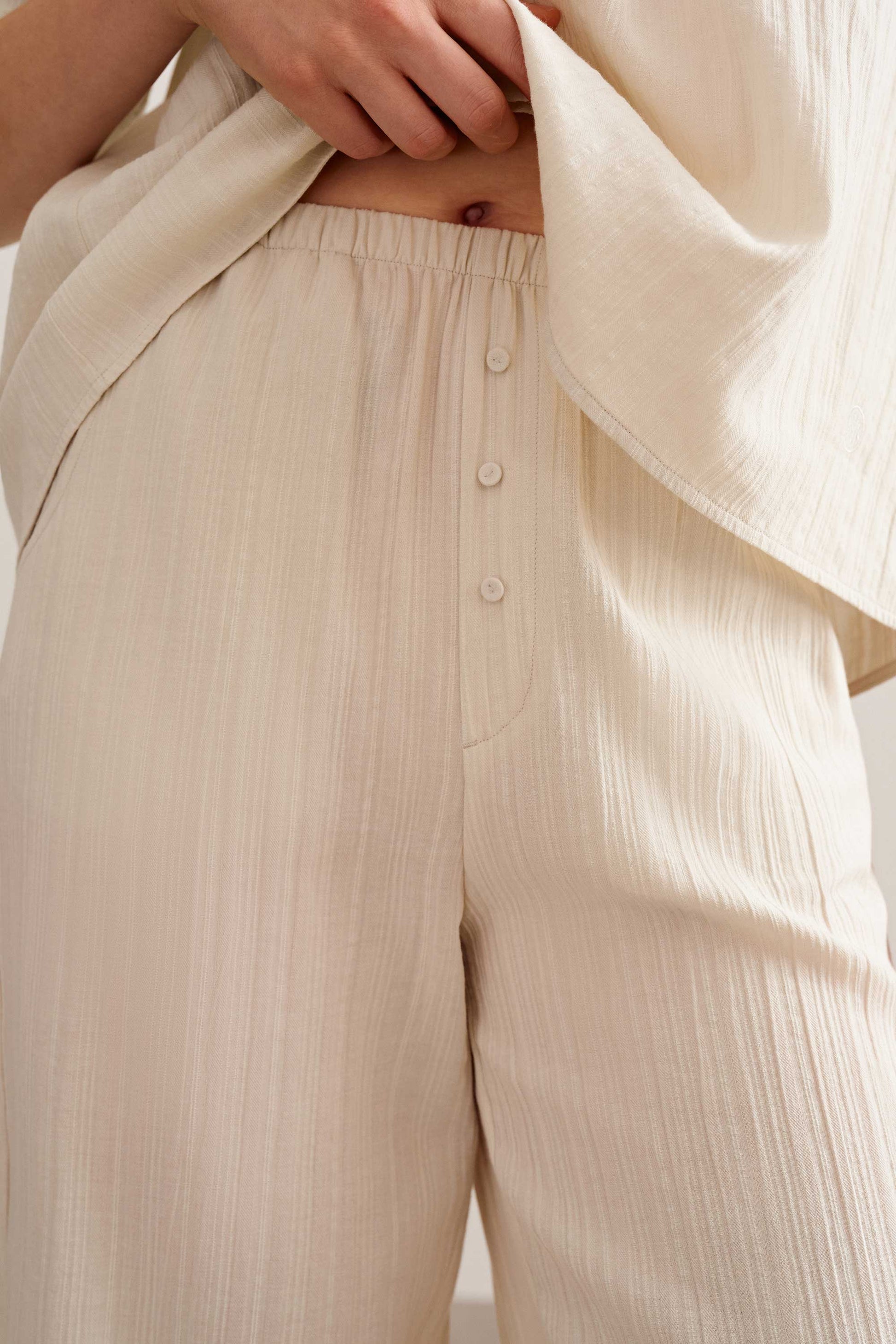 a woman wearing a light beige pants with three button. 