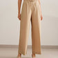 a woman wearing a beige tank tucked in light brown wide leg pants. pair with a white sandal. 