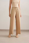 a woman wearing a beige tank tucked in light brown wide leg pants. pair with a white sandal. 
