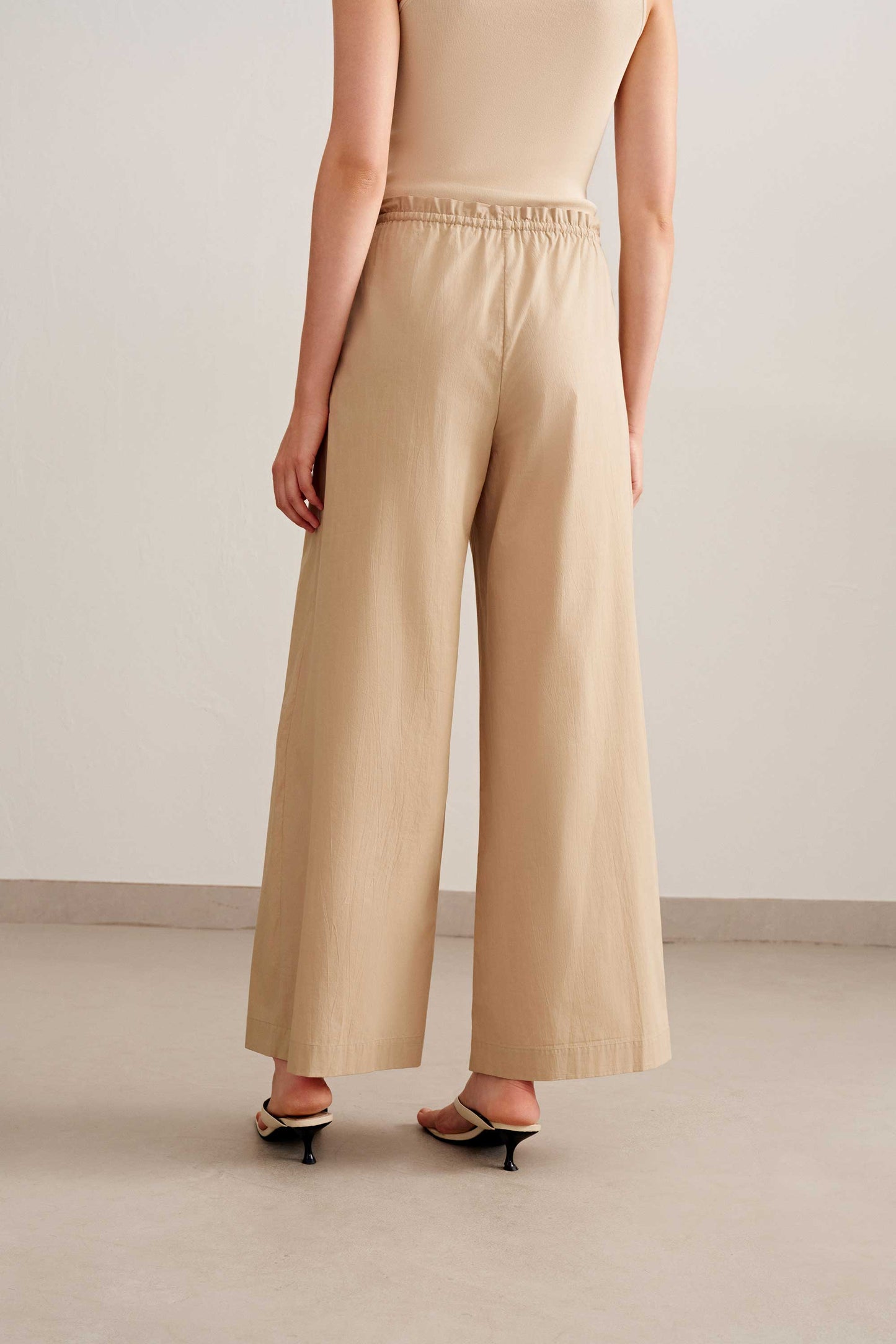 back of a woman wearing a  beige tank and light brown wide leg pants. Pair with a sandal 