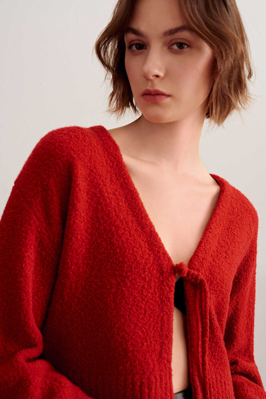 a woman wearing a red knot cardigan