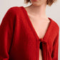 a woman wearing a red knot cardigan