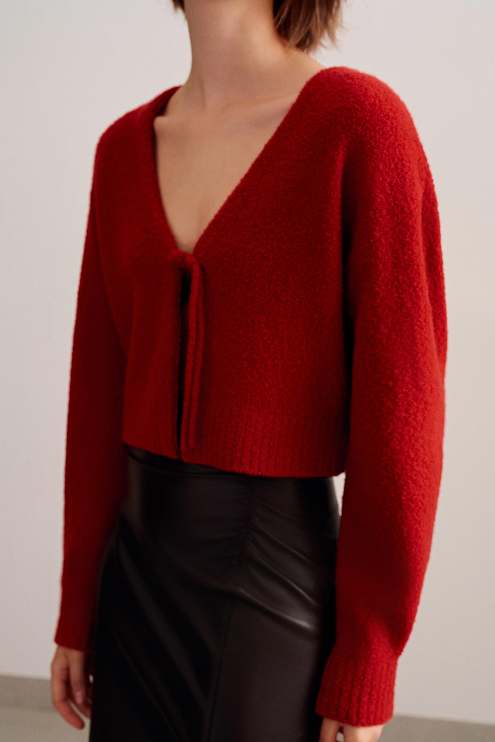 a woman wearing a red knot cardigan