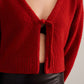 closeup shot of a woman wearing a red knot cardigan