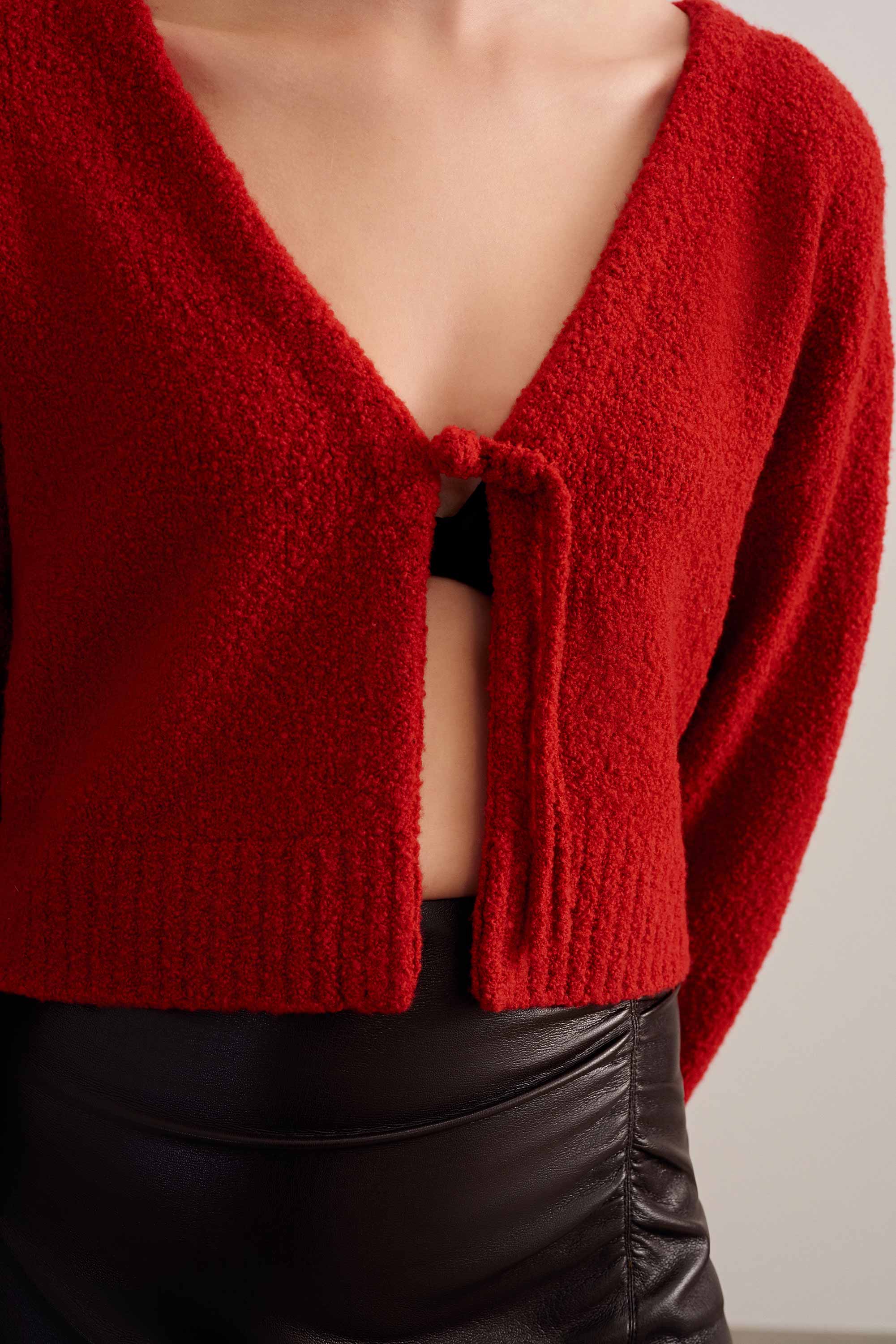 closeup shot of a woman wearing a red knot cardigan