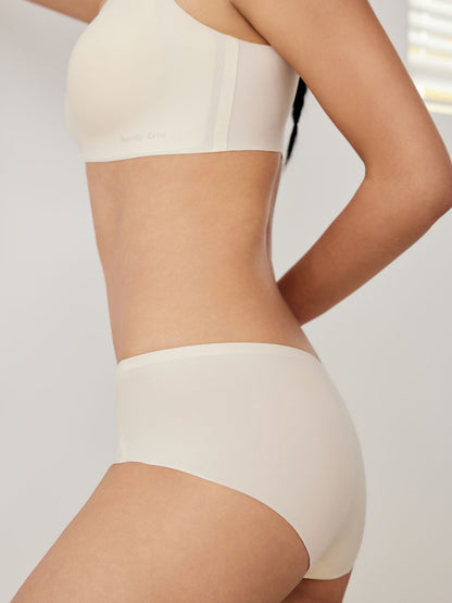Model wearing a white bra and brief set on a plain background.