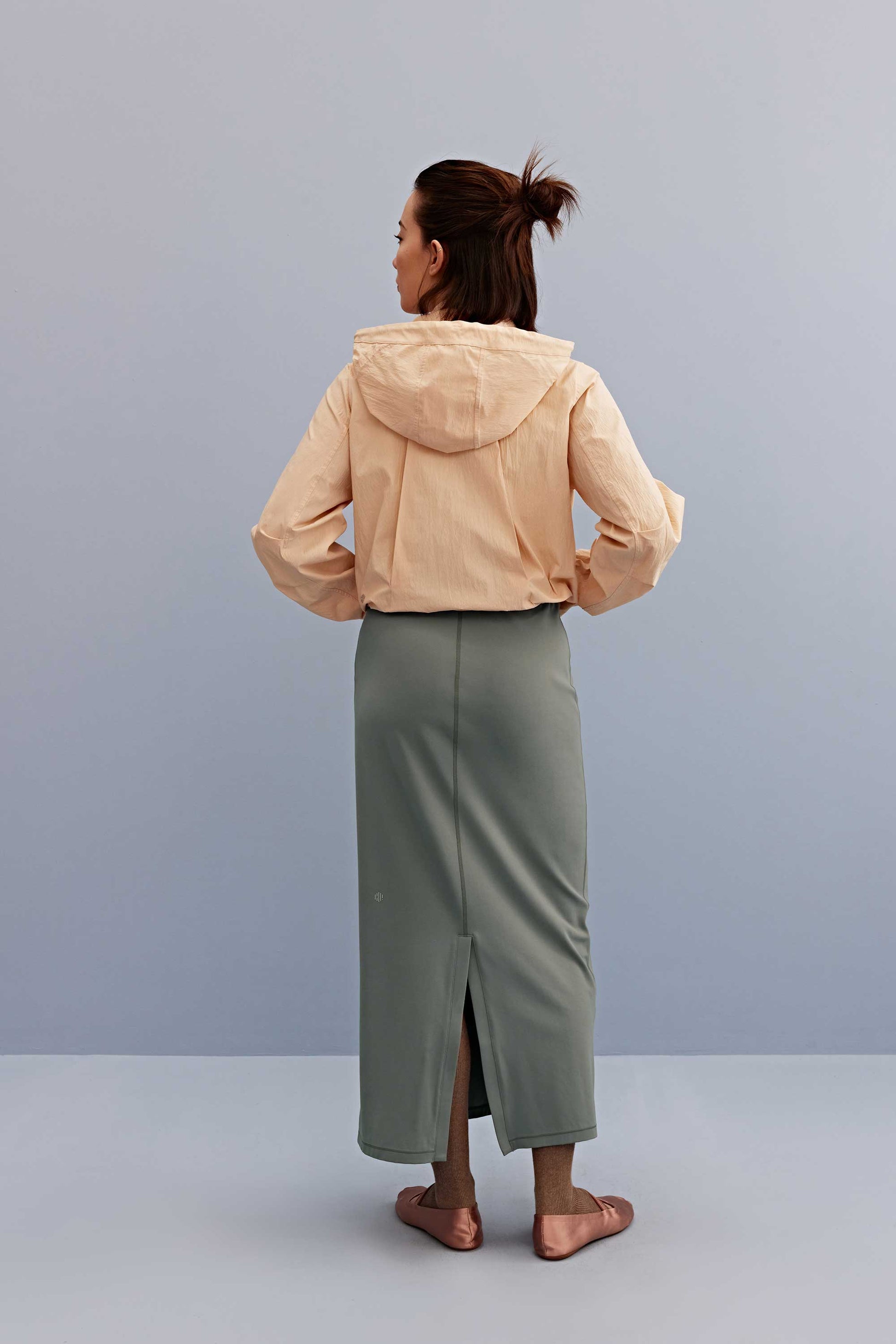 back of a woman wearing the warm yellow jacket and green skirt