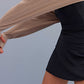 a woman stretch the shrug wearing a black sports bra and black skirt.