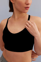 a woman holding the strap of the black sports bra
